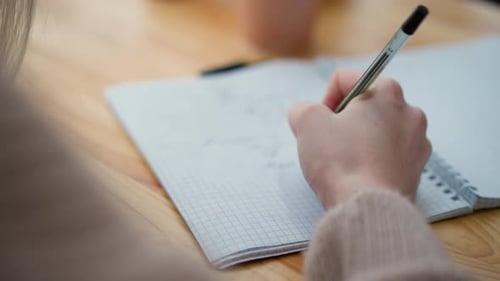 Closeup Hand Writing in Notebook with Blurred Background