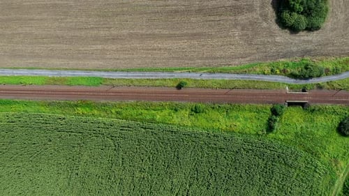 Aufnahme von oben nach unten von der Bahnstrecke, die durch landwirtschaftliche Felder führt