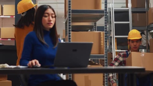 Asian Man in Wheelchair Moving Products in Warehouse