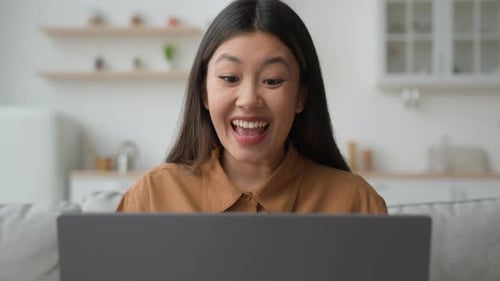 Woman Excited Using Laptop at Home on Couch