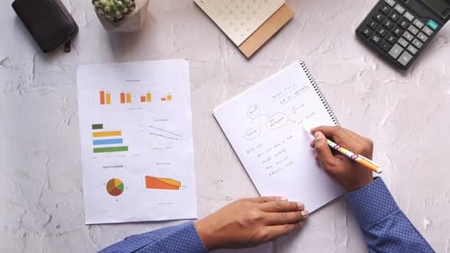 Vista superior de homens escrevendo no bloco de notas e analisando dados financeiros