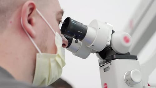 Closeup of Male Scientist in Protective Face Mask Using Microscope in Pharmaceutical Laboratory