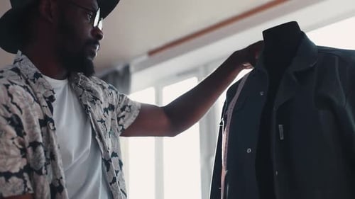 Fashionable Man Measuring Jacket on Mannequin Indoors