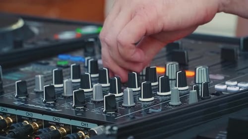 Professional DJ or producer turns up the volume of music close-up of fingers