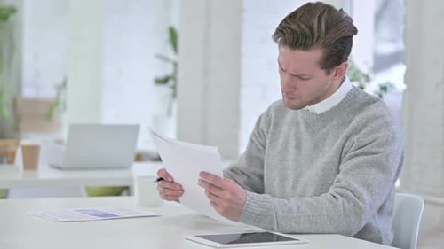Creative Young Man checking Financial Documents, Reading