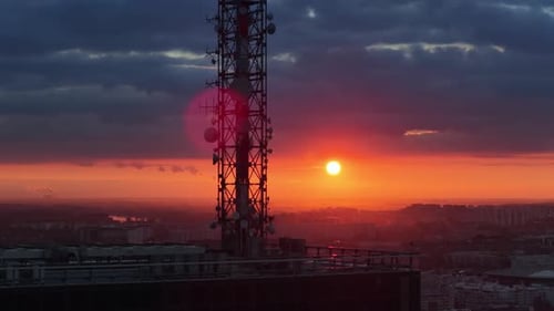 Aerial drone view of a large telecommunications tower set against an intense orange sunset over Belg