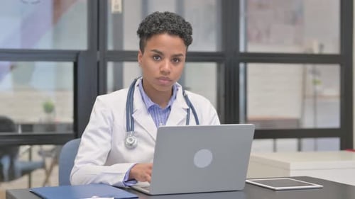 Female Doctor Works on Laptop in Bright Office
