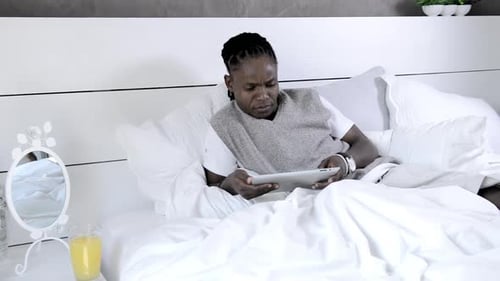 Man Relaxing in Bed Using Tablet Device