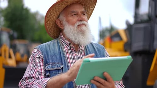 Senior Farmer Using Tablet Near Construction Equipment