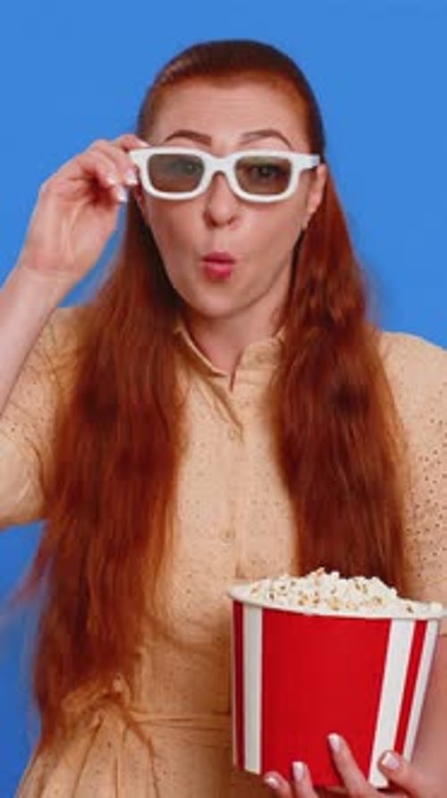 Femme adulte dans des lunettes 3D mangeant du pop-corn en regardant une série télévisée, un jeu de sport, un film, un contenu de film en ligne