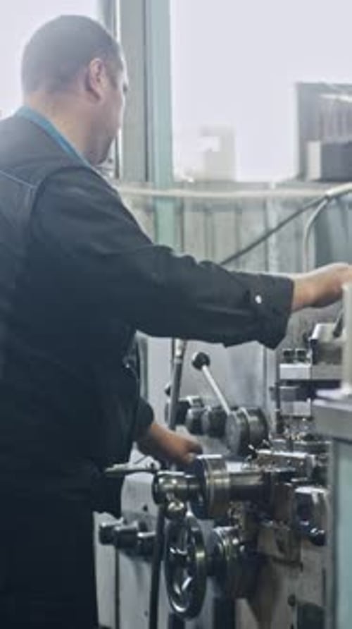 Metalworker using lathe in precision metal fabrication workshop