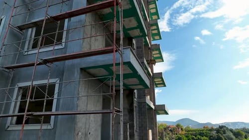 Los constructores trabajan de frente al edificio, se apoyan en el andamio