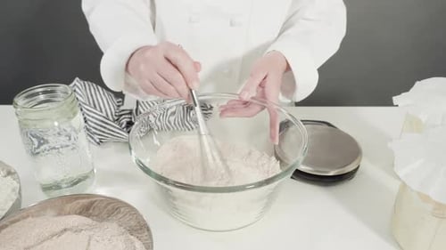 Mixing Flour with Whisk in a Glass Bowl