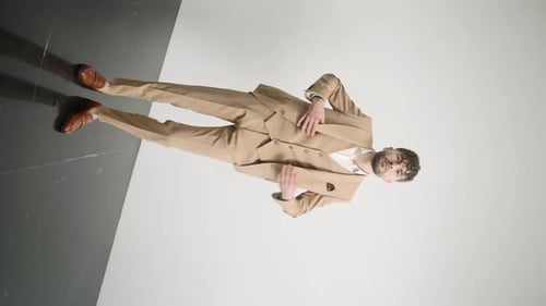 Man in tan suit standing on black surface