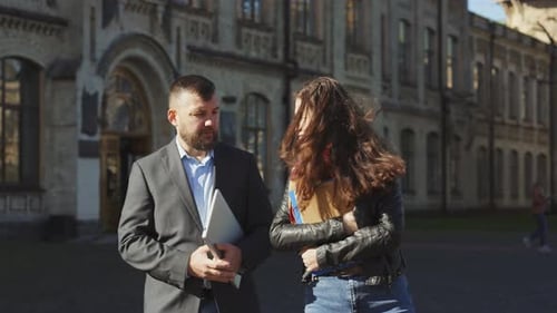 Bearded Teacher and Female Student in Discussion Walking Together