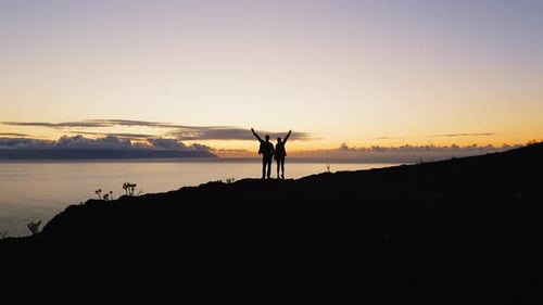 Couple Team Silhouette Two Tourists Climbed to the Top of Mountain and Raised Hands Up During Sunset