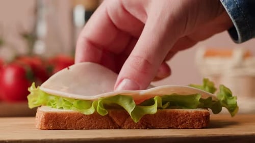 Close-up Sandwich Preparation with Meat and Cheese