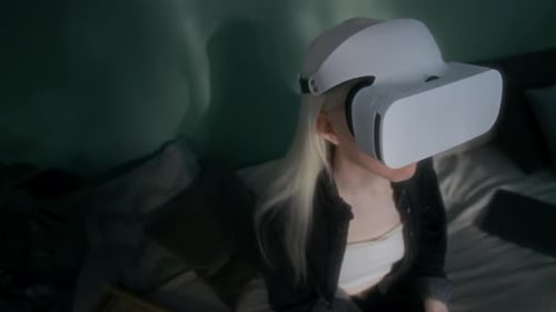 Young Adult Using Virtual Reality Headset on Bed