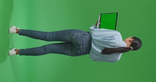 Back View Of Full Body Asian Woman Using Laptop With Mock Up Green Screen On Green Screen Studio