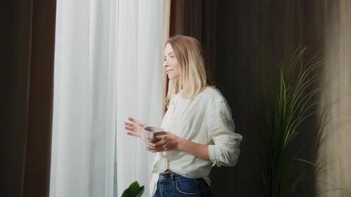 Charming Happy Young Woman Drinking Coffee at Home Enjoying Relaxed Morning Looking Out Window
