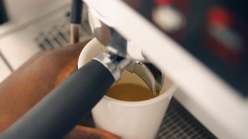 Extreme close up of Barista taking out mug from industrial coffee portafilter handle after espresso