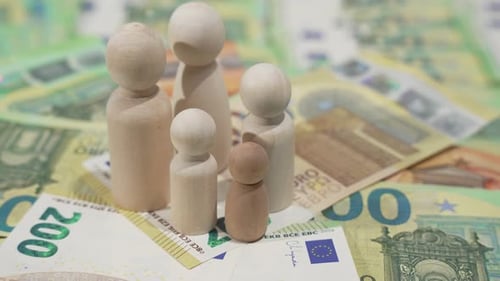Rotating wooden peg people stand on euro cash, concept of family finance, income and expenses.