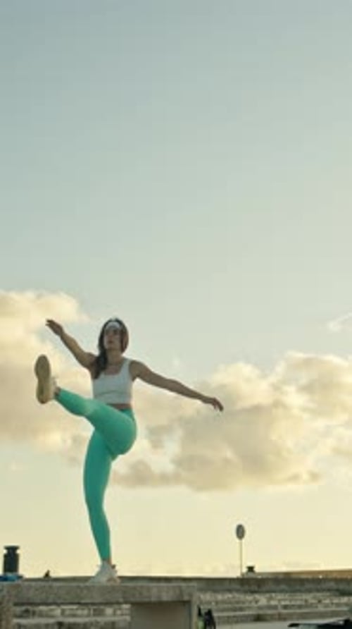 Athletic Woman Stretching and Exercising Outdoors at Sunset