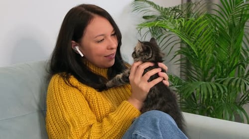 Woman Cuddling Kitten on Gray Sofa Indoors