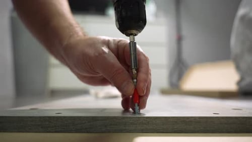 A man screws a screw into wood.