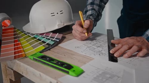 Mann am Tisch mit Lineal und Bleistift in der Hand zeigt Ingenieurgeste