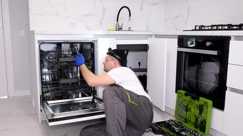 Professionelle Reparatur von Geschirrspülern Ein Mechaniker repariert einen Geschirrspüler in der Küche