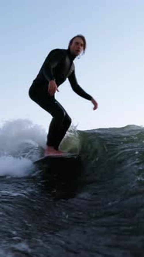 Dynamic Surfing Action A Skillful Surfer Riding a Thrilling Wave Against a Clear Sky Capturing the