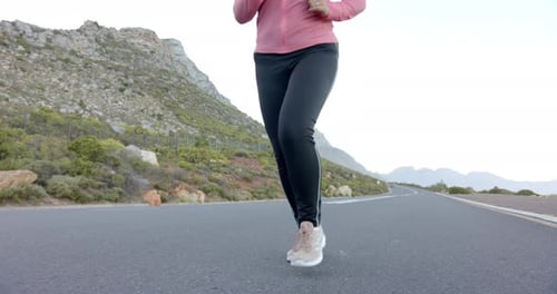 Jogging on mountain road, woman in pink jacket enjoying outdoor exercise