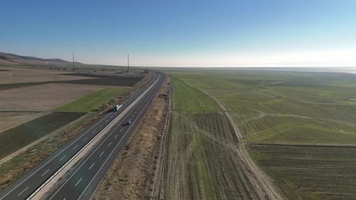 A Single Car Journeys Along a Smooth Highway Surrounded By Green Farmlands