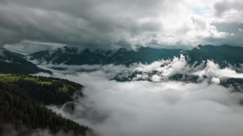 Hyperlapse of moving cloud layers in a mountain valley with the sun peeking through the top cloud la