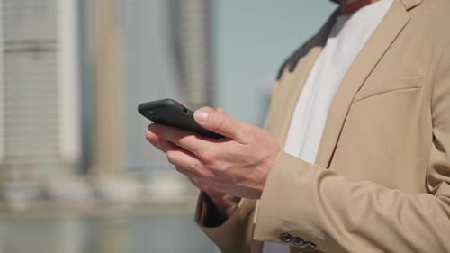 Businessman with Smartphone in Hands Closeup View Against Urbanscape Successful Man Using Phone