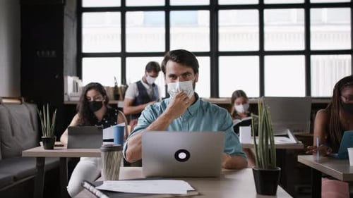 Young business team working in office with face masks during coronavirus pandemic