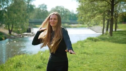 Woman Dancing Outdoors in Park by River