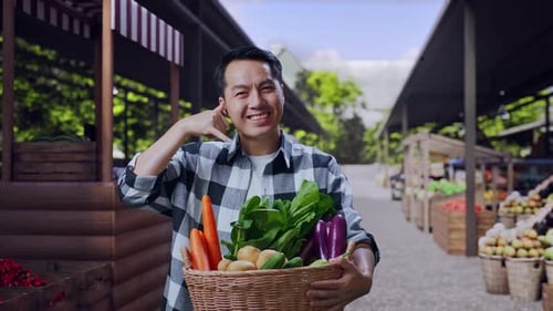 Asian Male Farmer With Vegetable Basket Talking On The Telephone Gesture At Small Market