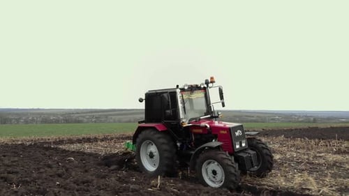 Roter Traktor pflügt das Feld in der Ukraine