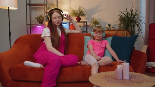Woman and Girl Relaxing on Couch Listening to Music