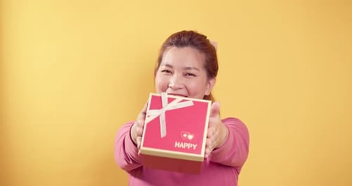 Cheerful Woman Presents Gift Box With A Smile
