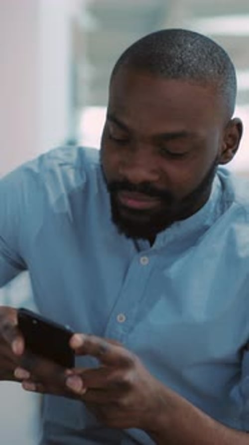 Man Smiling and Using Smartphone Indoors