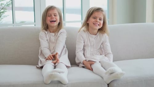 Two Smiling Girls Sitting Together on a Couch