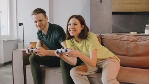 Couple Play Video Game Together on Couch at Home