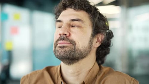 Close up of bearded businessman relaxing with closed eyes in sitting at workplace business office.