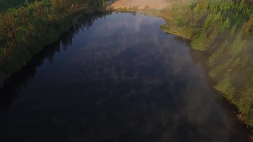 Misty morning sunlight over autumn forest lake and scenic countryside landscape aerial wide view