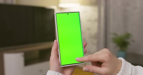 Closeup of Woman Hands Holding Smartphone with Green Screen in Vertical Position