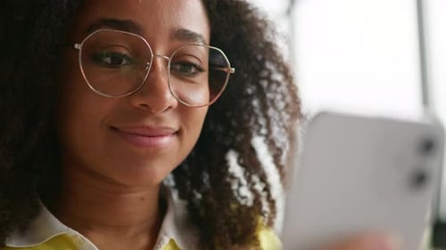 Smiling Woman Looks at Her Mobile Phone