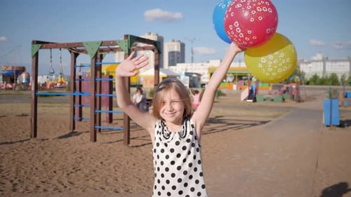 Happy Little Girl with Balloons Having Fun on Playground in Summer